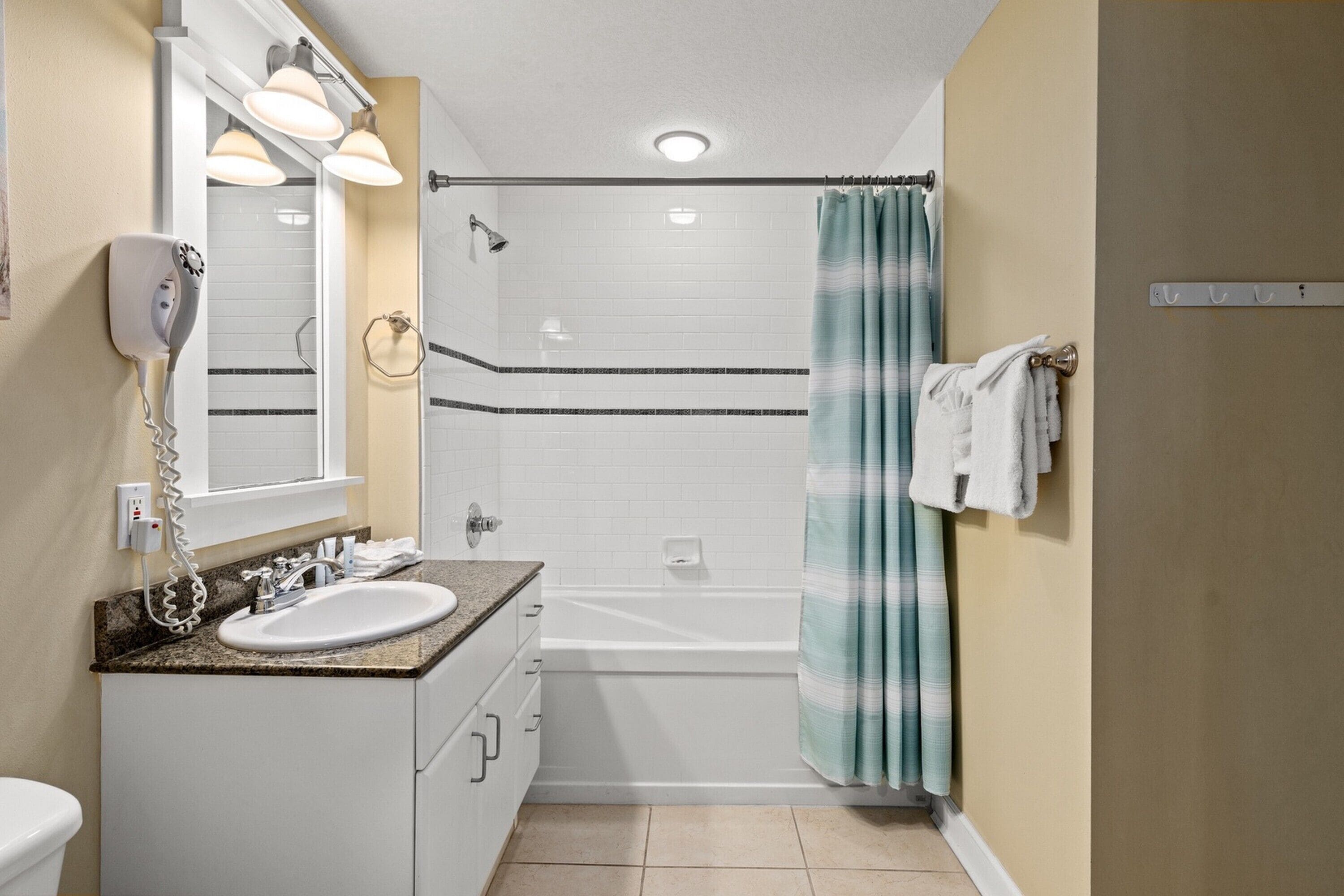 A bathroom with a sink, mirror, and shower.