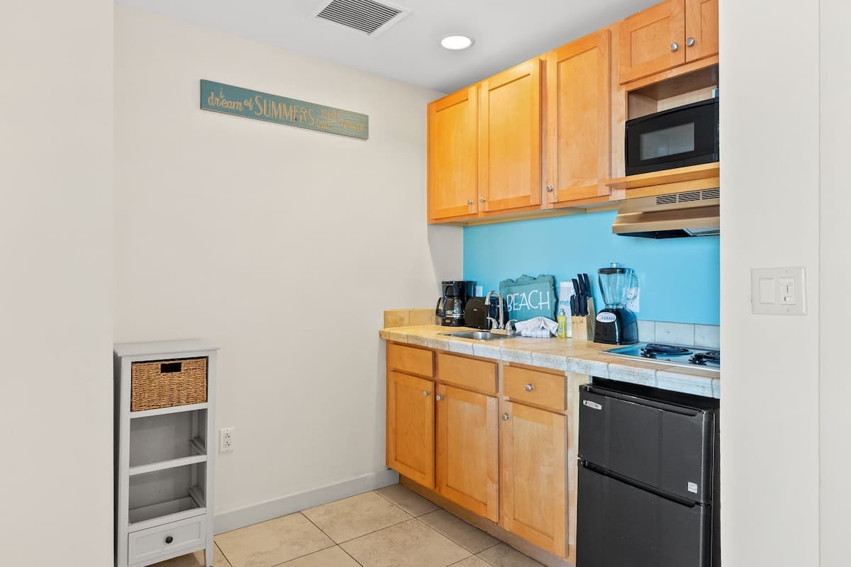 A kitchen with wooden cabinets, a black refrigerator, a microwave, and a coffee maker.