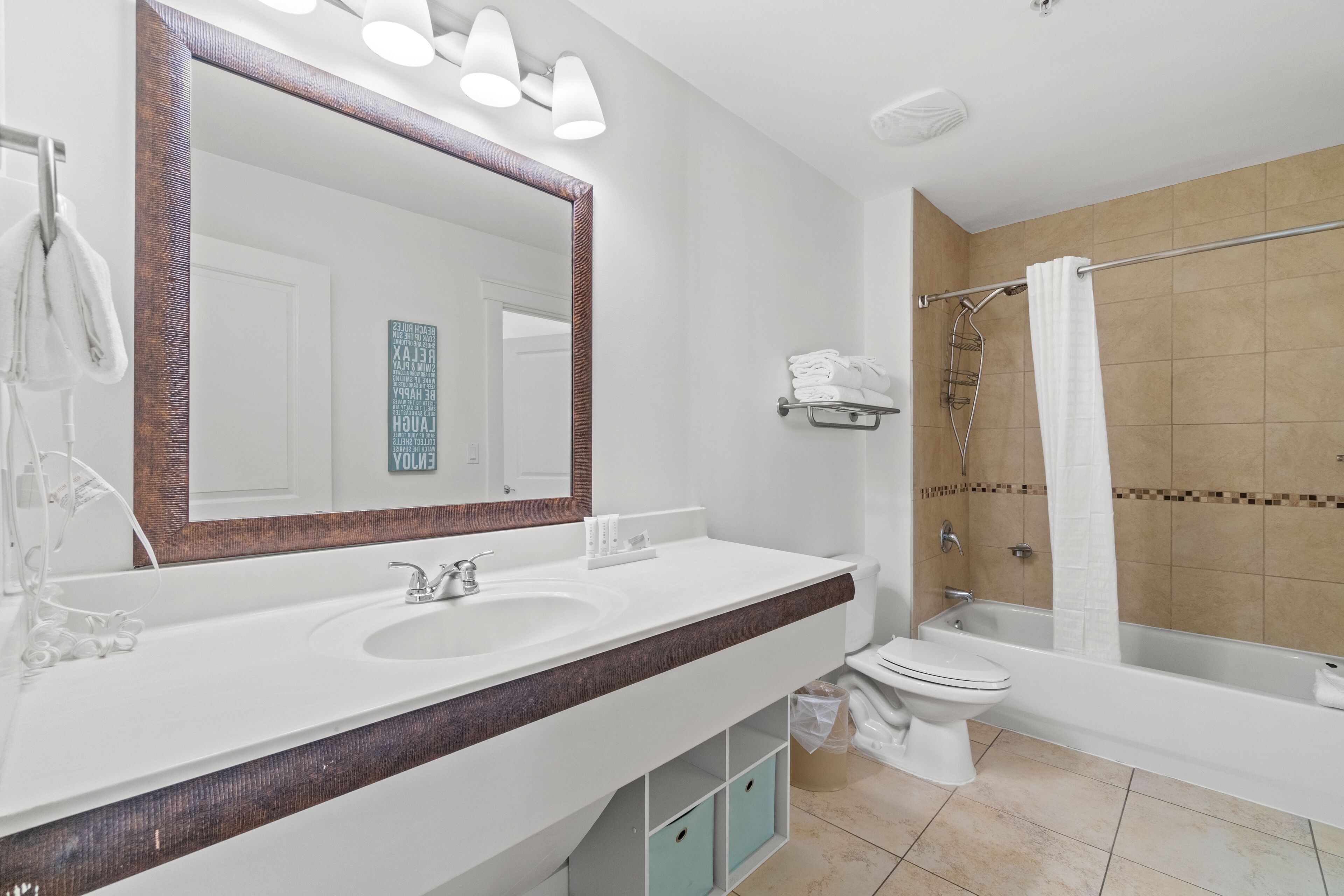 A modern bathroom with a large mirror, two sinks, a toilet, and a bathtub.