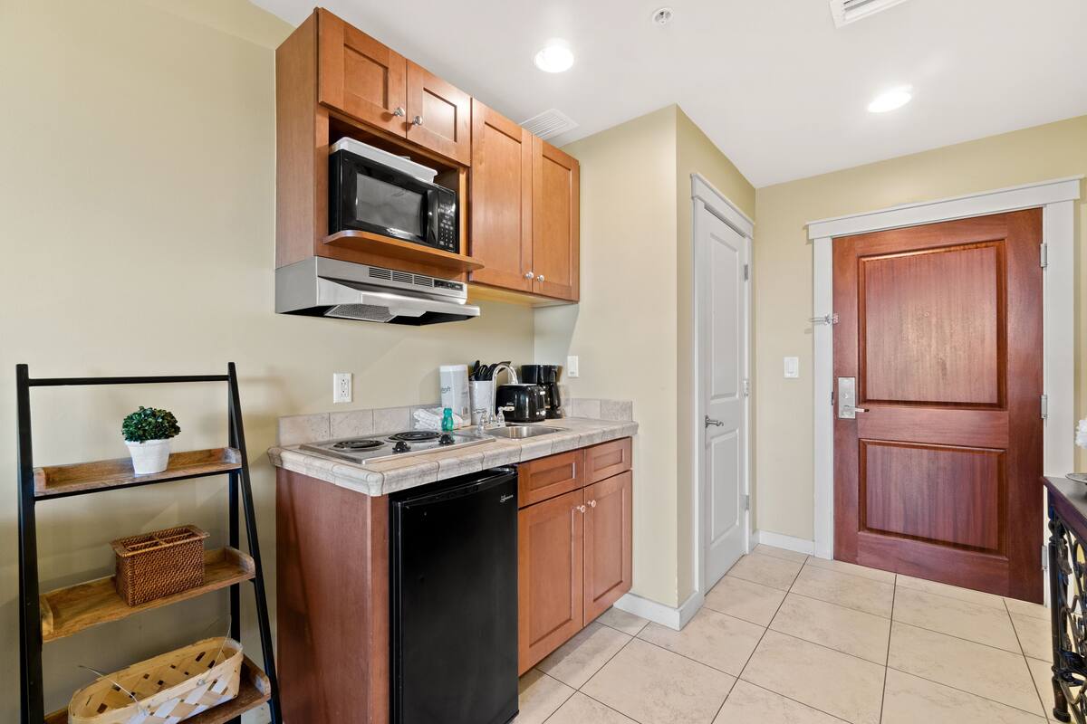 A compact kitchen with wooden cabinets, a built-in microwave, a dishwasher, and a coffee maker.