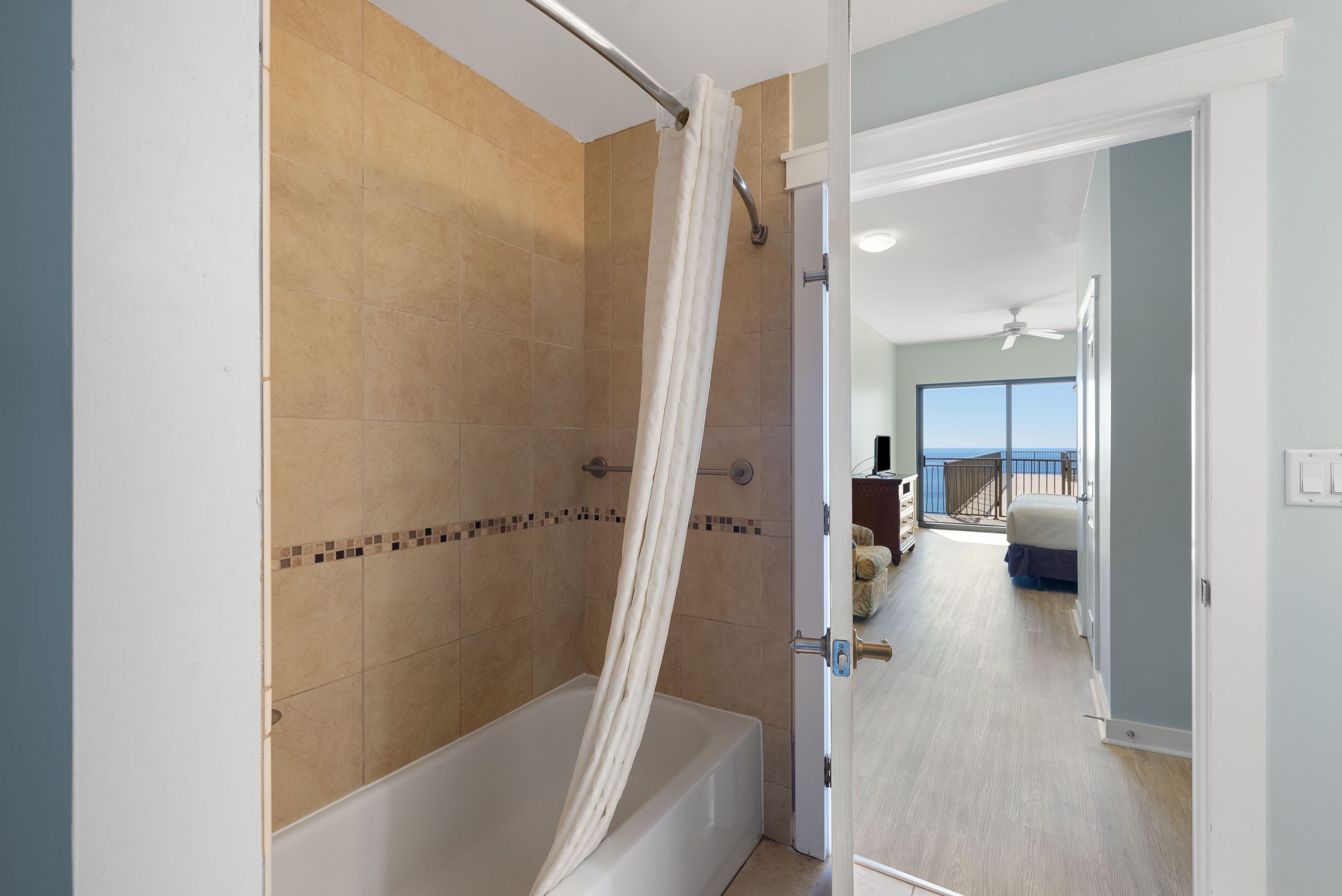 A modern bathroom with a bathtub, shower curtain, and tiled walls.