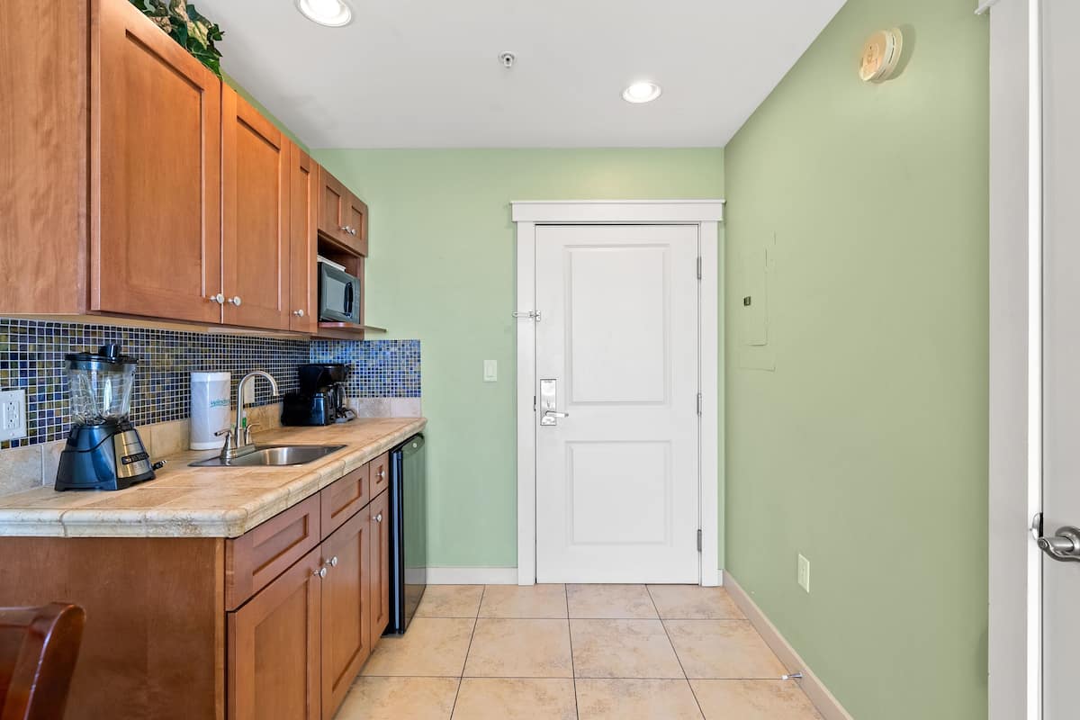 A kitchen with wooden cabinets, a microwave, a blender, and a sink.