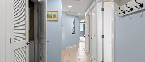 A hallway with white doors, a coat rack, and a sign reading "BEACH HOUSE".
