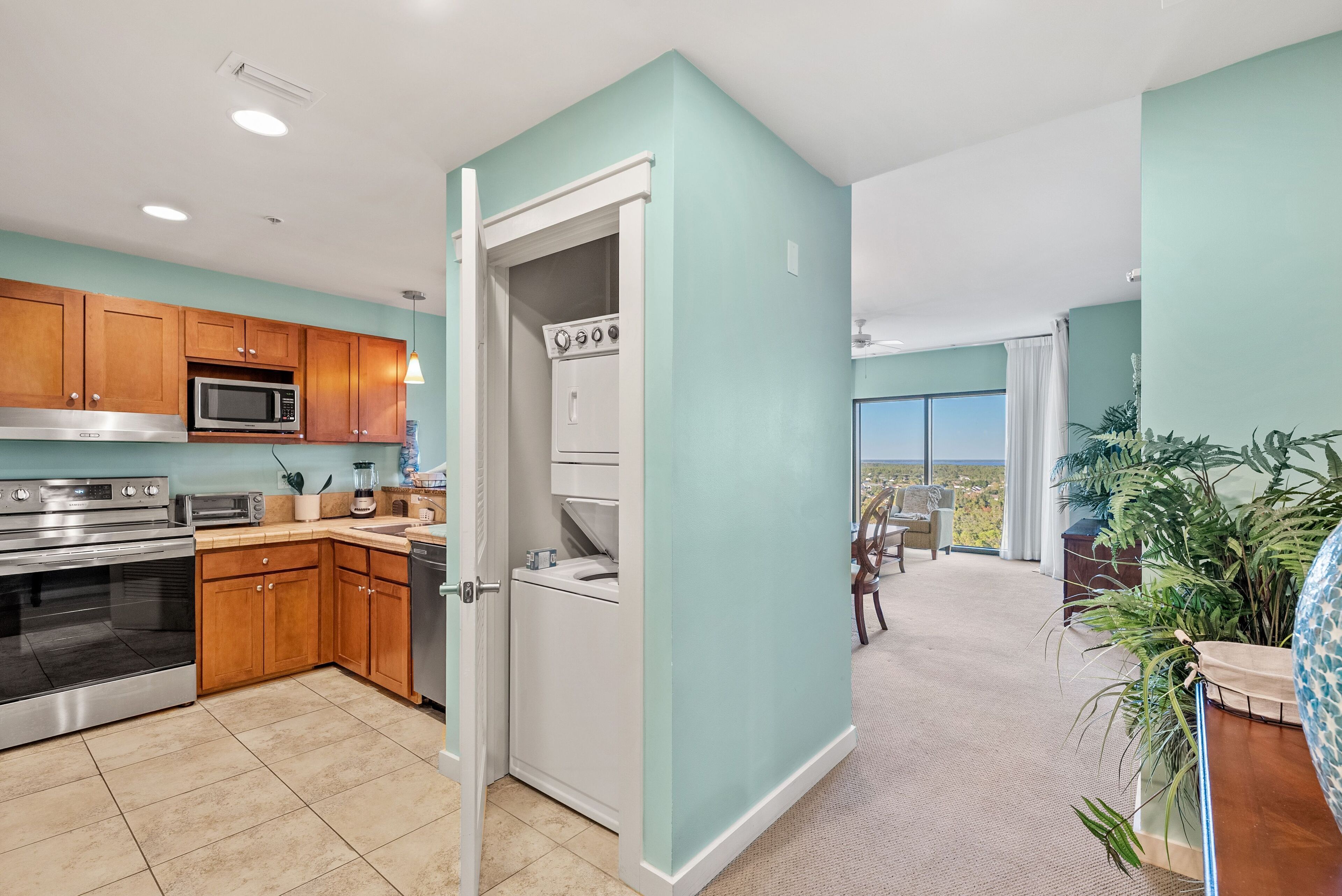 A modern kitchen with wooden cabinets, stainless steel appliances, and a view to the living area.