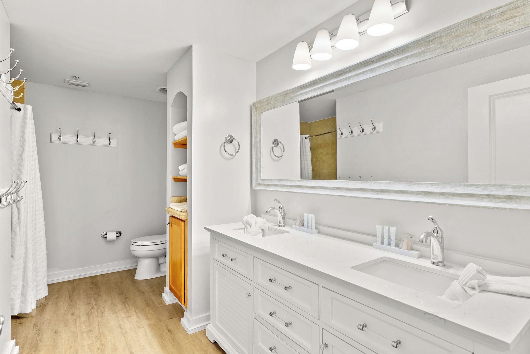 Une salle de bain moderne avec un meuble-lavabo blanc, un grand miroir et un espace douche.