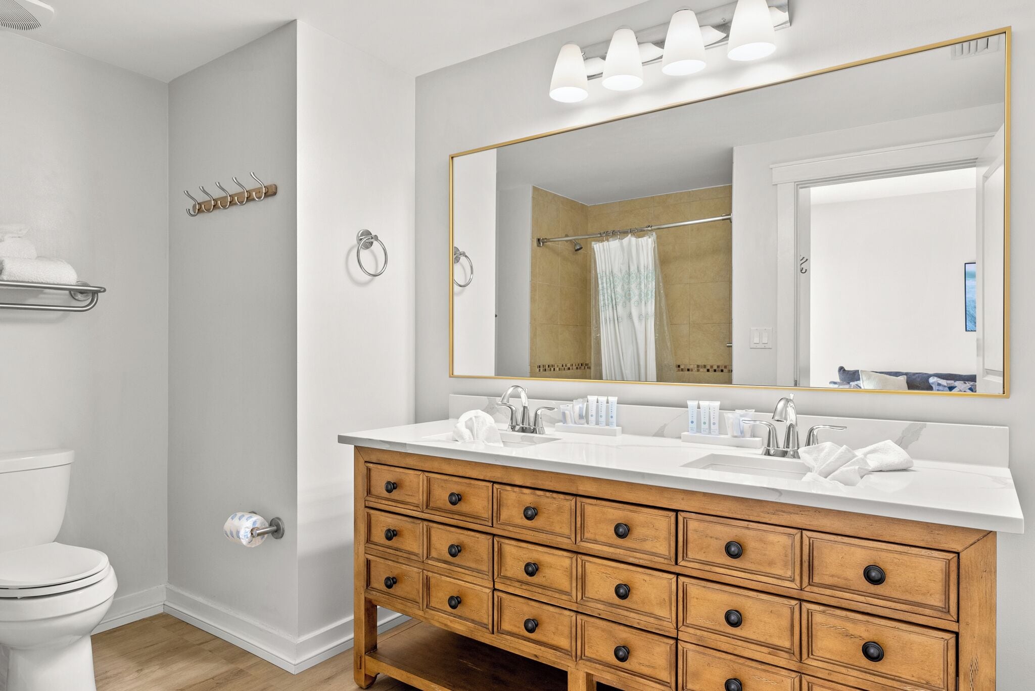 A modern bathroom with a wooden vanity, a large mirror, and a shower area.