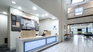 A modern reception area with a counter, seating, and a view to a balcony.