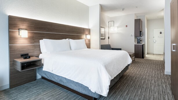 A modern hotel room with a large bed, bedside tables, a desk, and a microwave.