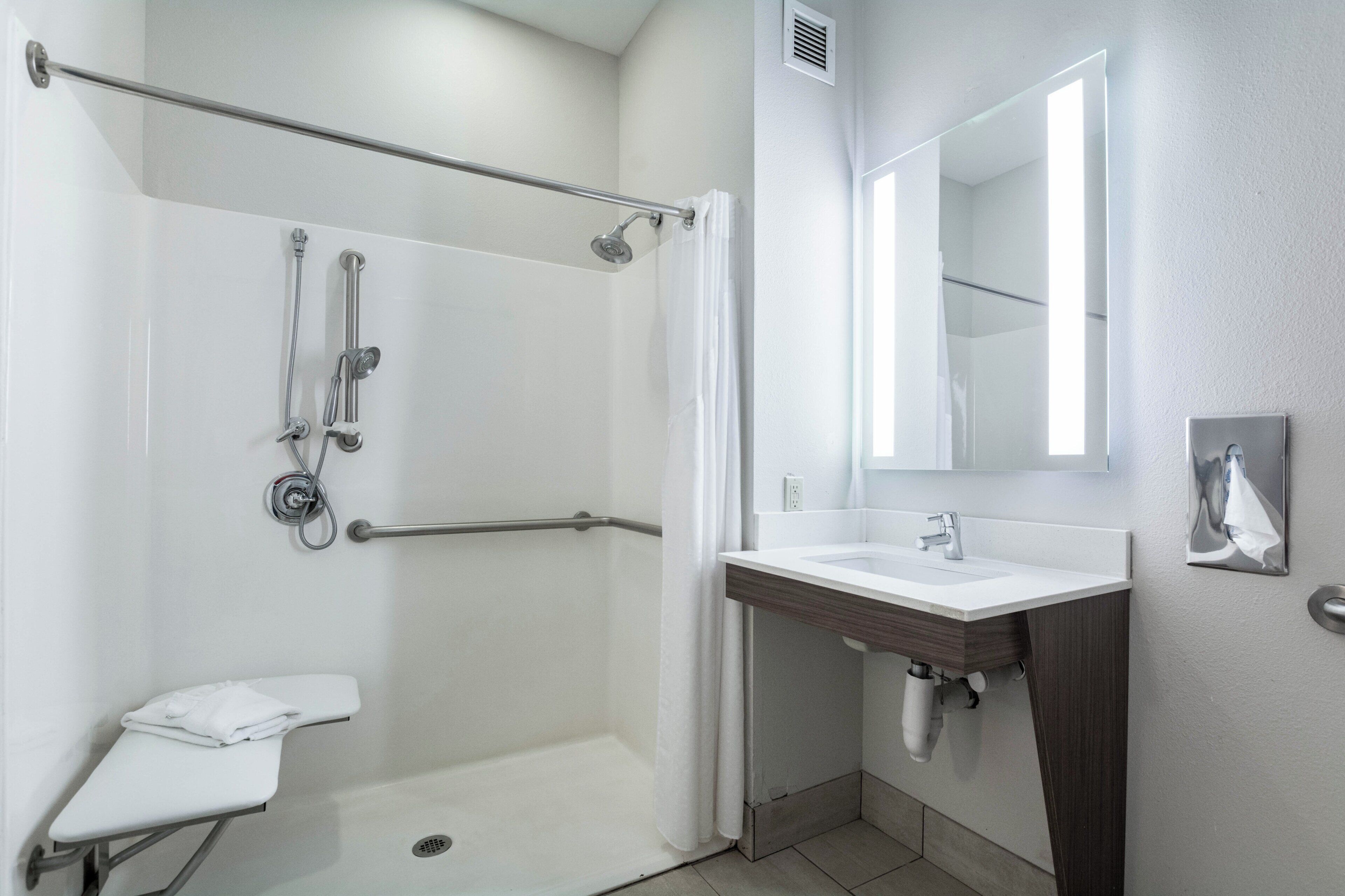 A modern bathroom with a walk-in shower, a sink, and a mirror.