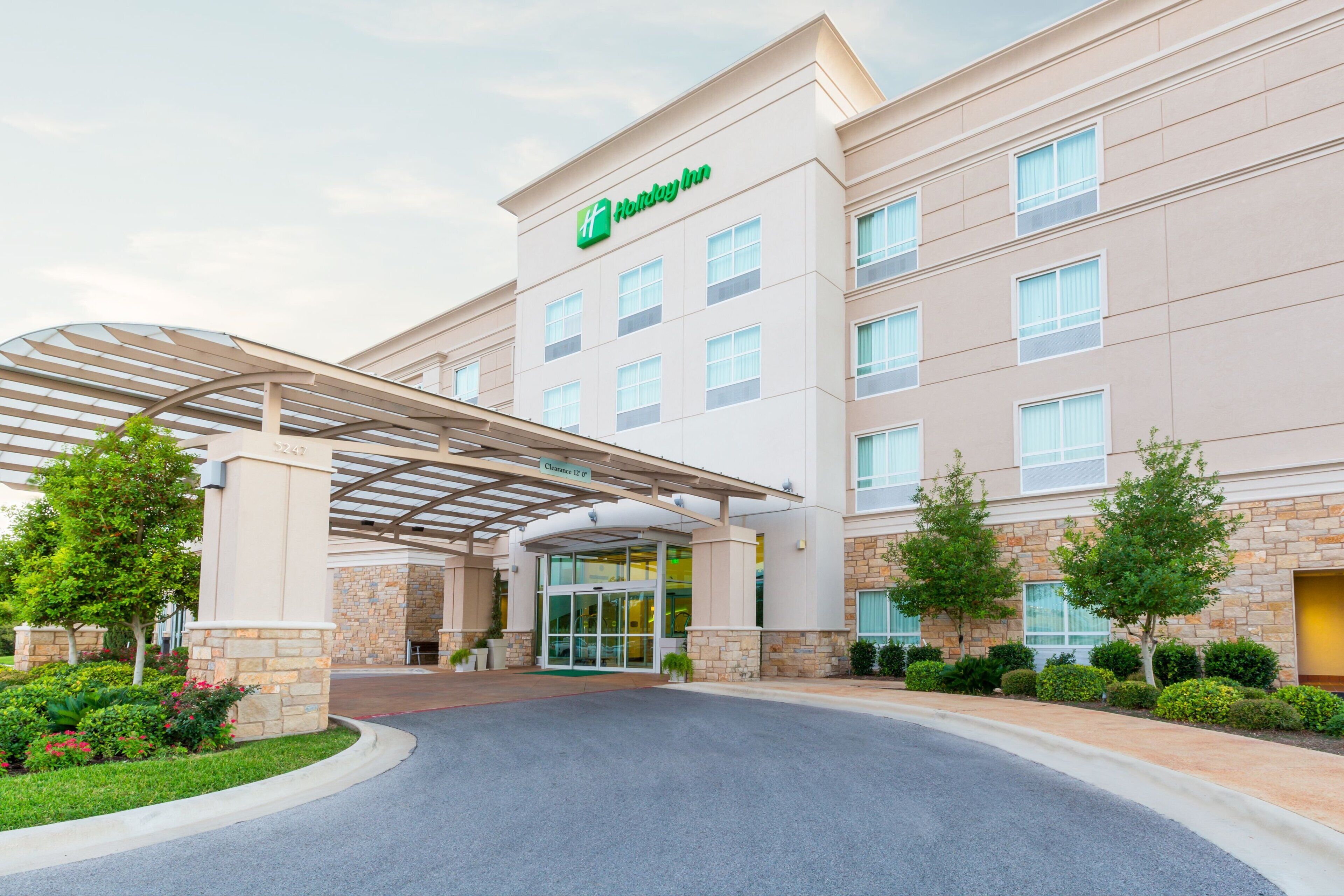 A Holiday Inn Express hotel with a covered entrance, stone facade, and a clear sky.