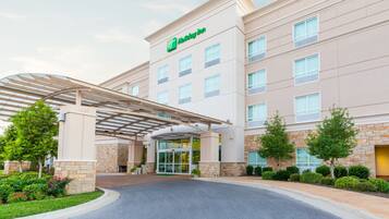 A Holiday Inn Express hotel with a covered entrance, stone facade, and a clear sky.