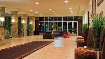 A spacious lobby with a stone column, seating area, and large windows.