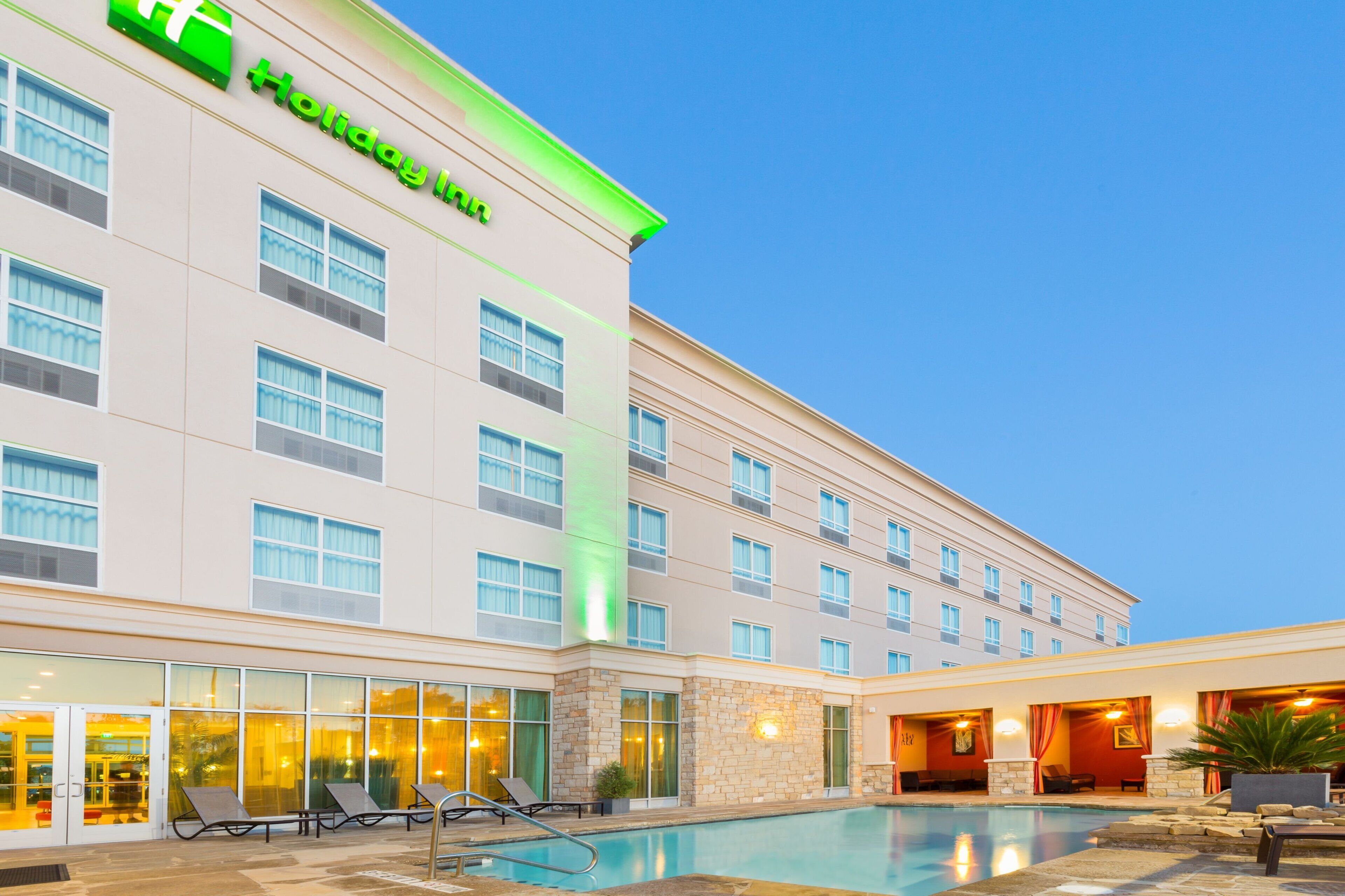 Un hôtel Holiday Inn doté d’une piscine, d’un espace extérieur aménagé et d’une entrée bien éclairée.