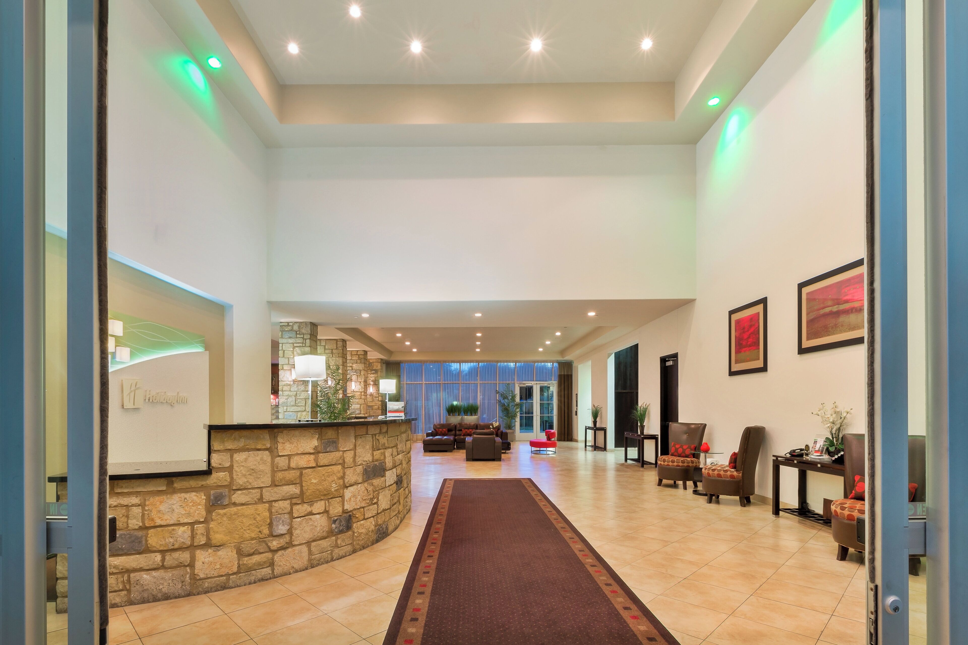 A hotel lobby with a stone reception desk, a seating area with sofas, and a large window.