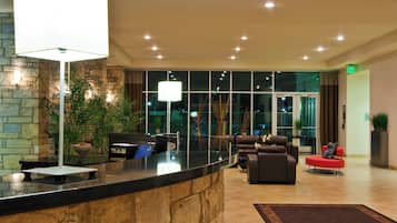 Un hall de hotel con mostrador de recepción, zona de estar y amplios ventanales.