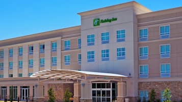 A Holiday Inn hotel with a covered entrance, multiple floors, and a clear sky.