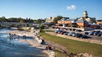 Une vue sur la rivière, avec un pont, un parking et des bâtiments, dont un imposant édifice surmonté d’un dôme.