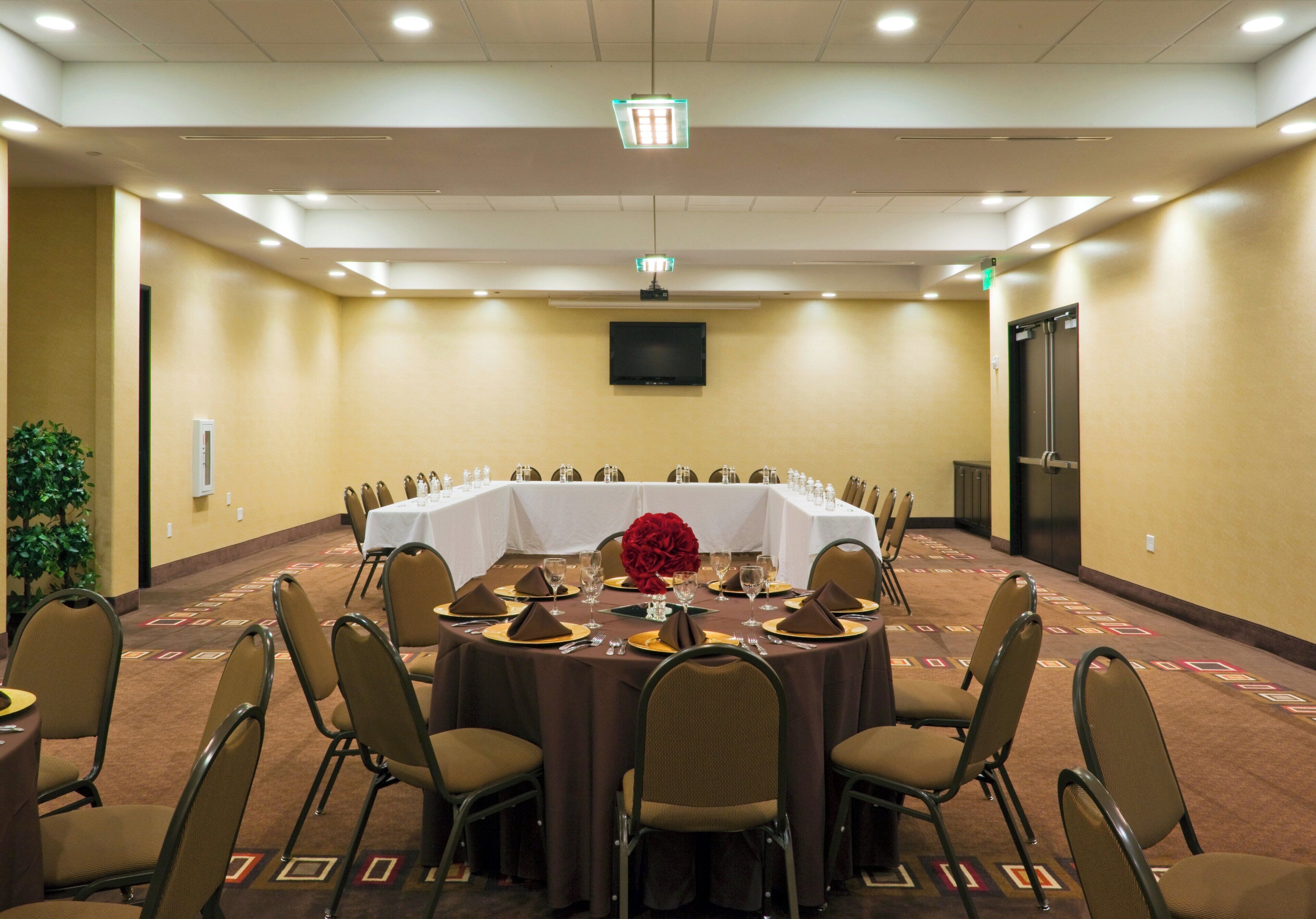 A conference room with a round table, chairs, and a large floral centerpiece.