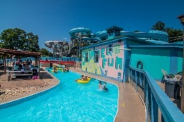 Un parc aquatique avec une piscine, des toboggans et un bâtiment portant l’inscription « AMUSEMENT ».