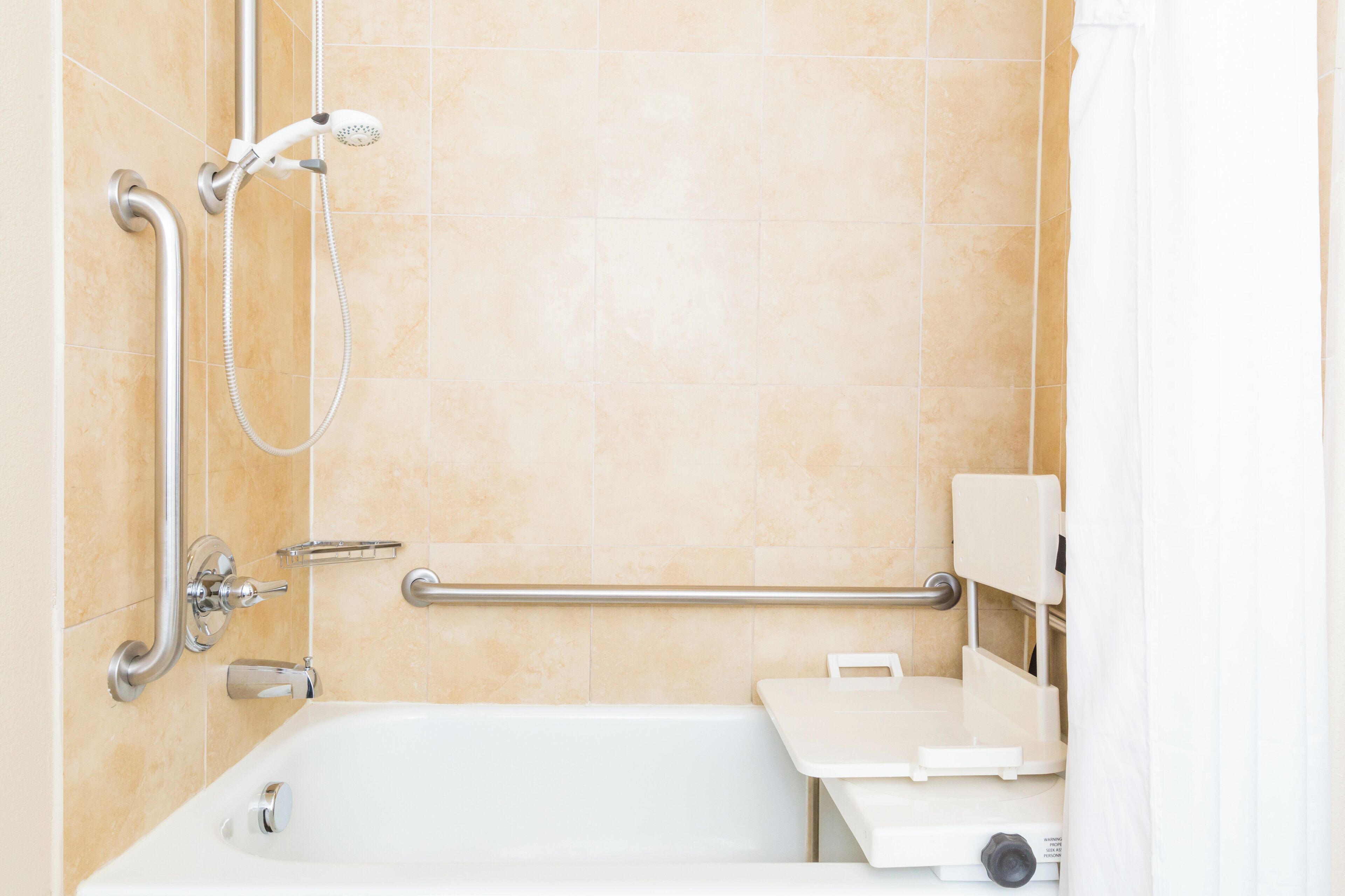 Un baño con bañera, ducha y barra de apoyo.