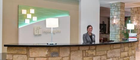 Una recepción con pared de piedra, un cartel que dice "Hotel Inn" y una lámpara moderna.