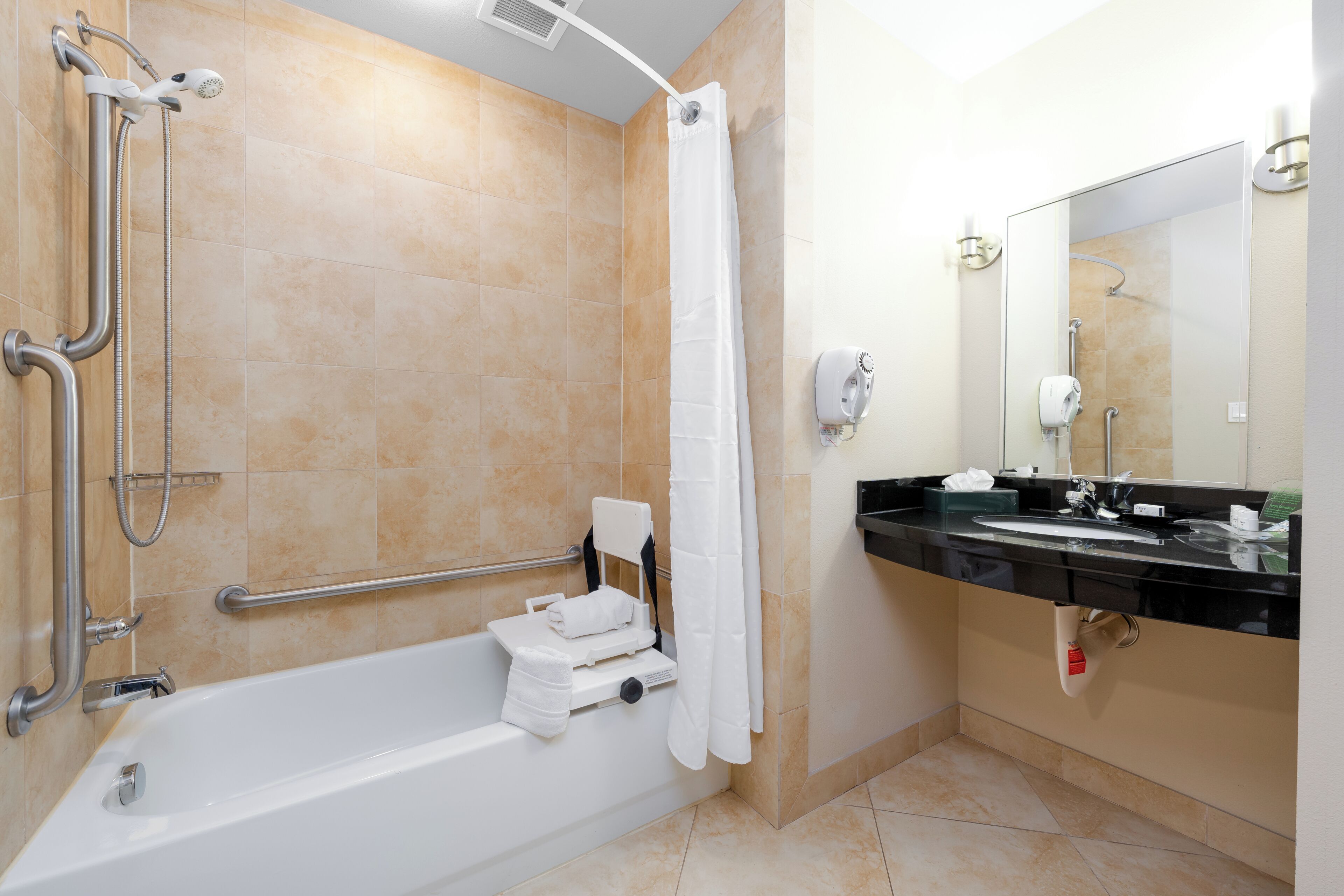 A modern bathroom with a walk-in shower, grab bars, a bathtub, a vanity with a mirror, and a towel rack.