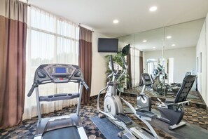 Une salle de sport équipée de tapis de course, de vélos elliptiques et d’un vélo d’appartement.