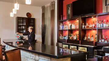 A bar area with a bartender, shelves of liquor bottles, and a television mounted on the wall.
