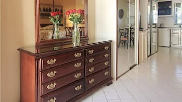 A spacious room with a large wooden dresser, a mirror, and a vase with flowers.