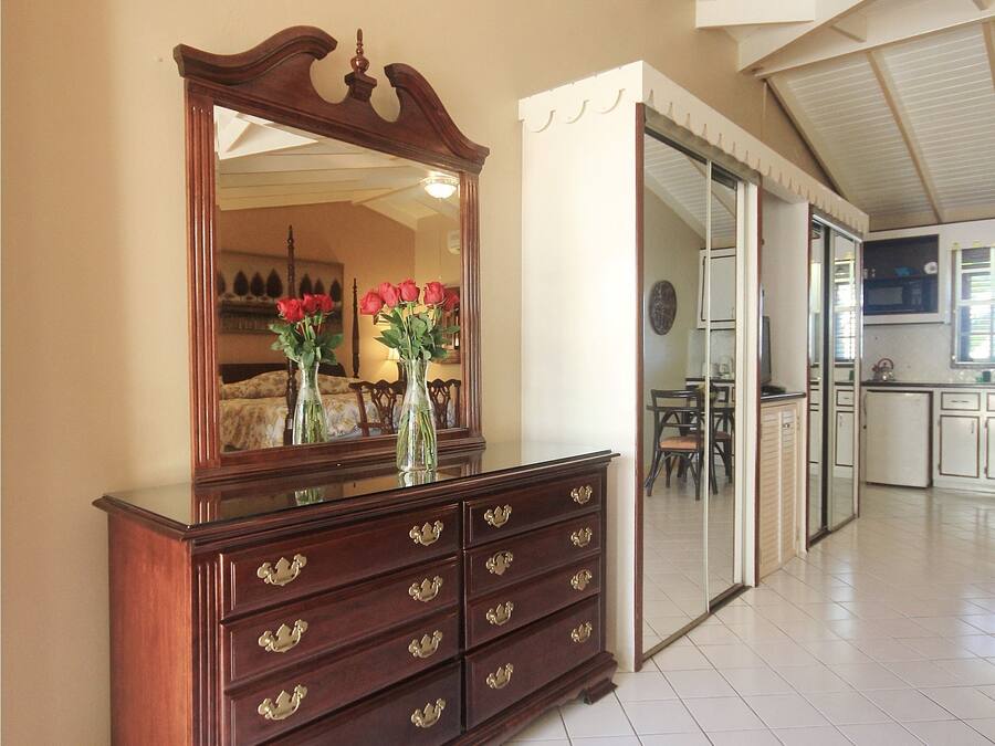 Ein geräumiges Zimmer mit einem großen Holzschrank, einem Spiegel und einer Vase mit Blumen.