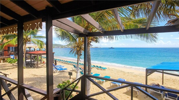 A beach view from a covered area with palm trees and a clear blue sea. - Mary's Boon Beach Resort & Spa (Simpson Bay)