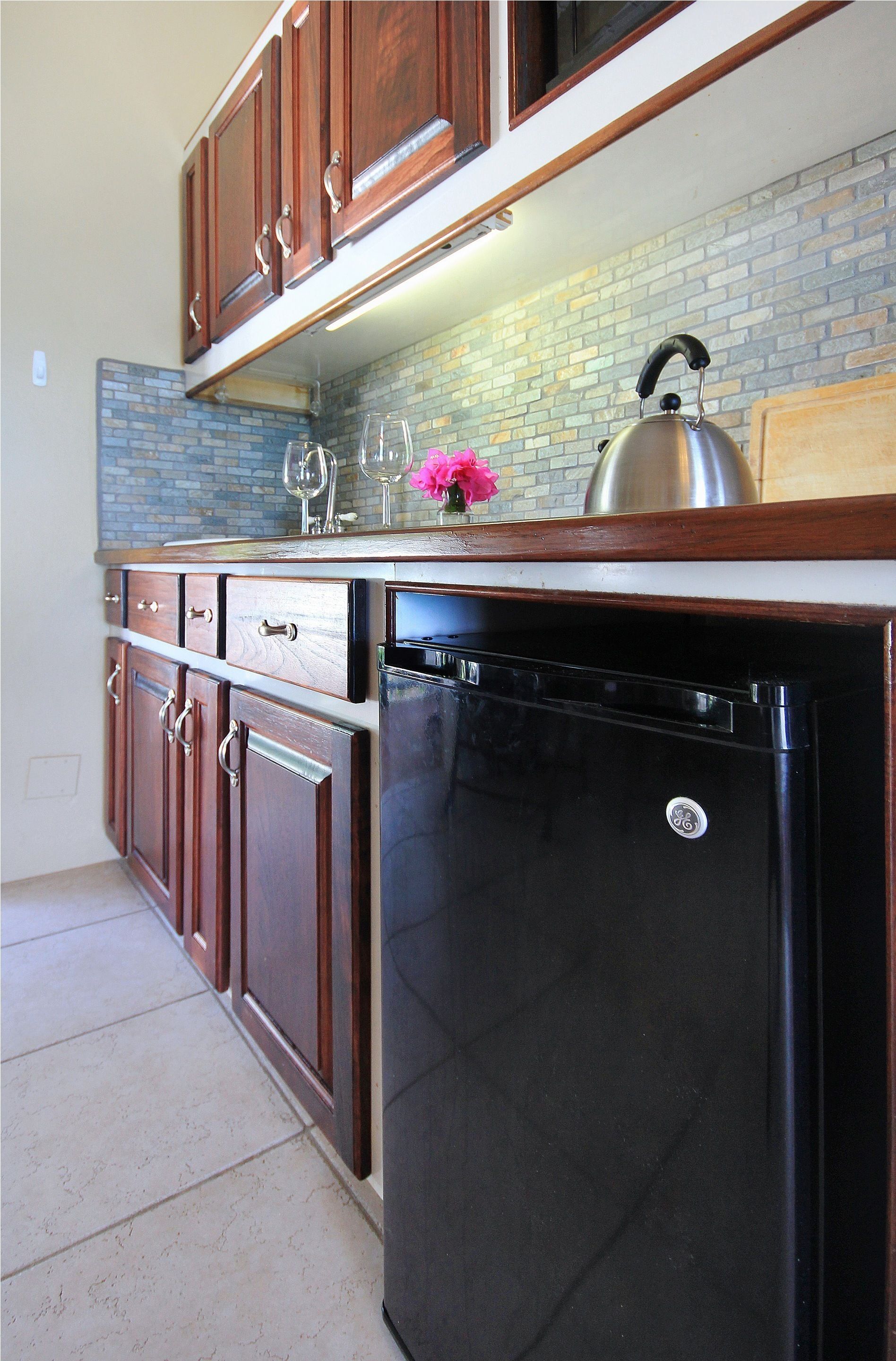 A kitchen with wooden cabinets, a black dishwasher, and a brick backsplash.