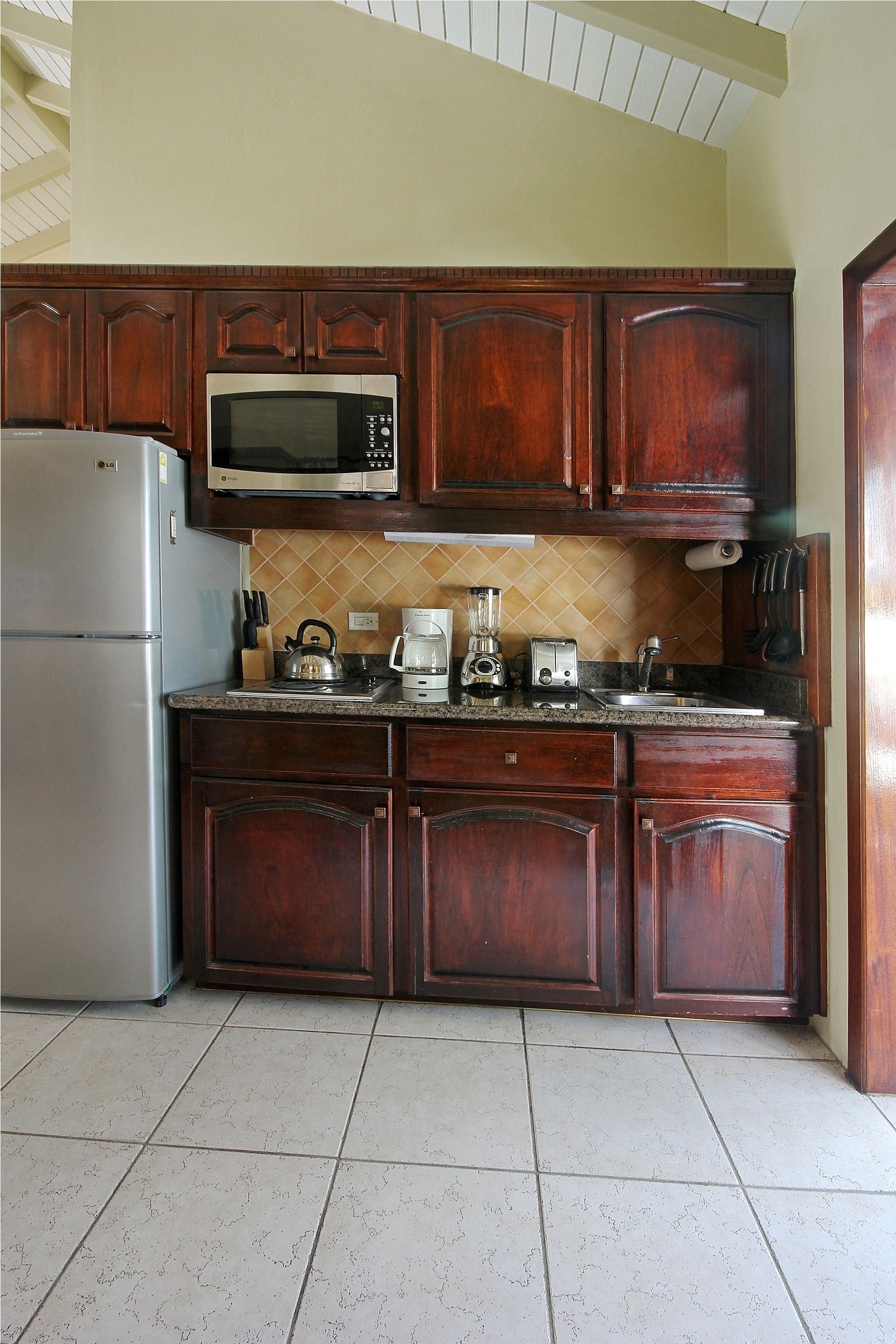 Una cocina con armarios de madera, un refrigerador de acero inoxidable, un microondas, una cafetera y un tostador.