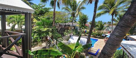 A resort with a pool, palm trees, and a covered area with a railing.