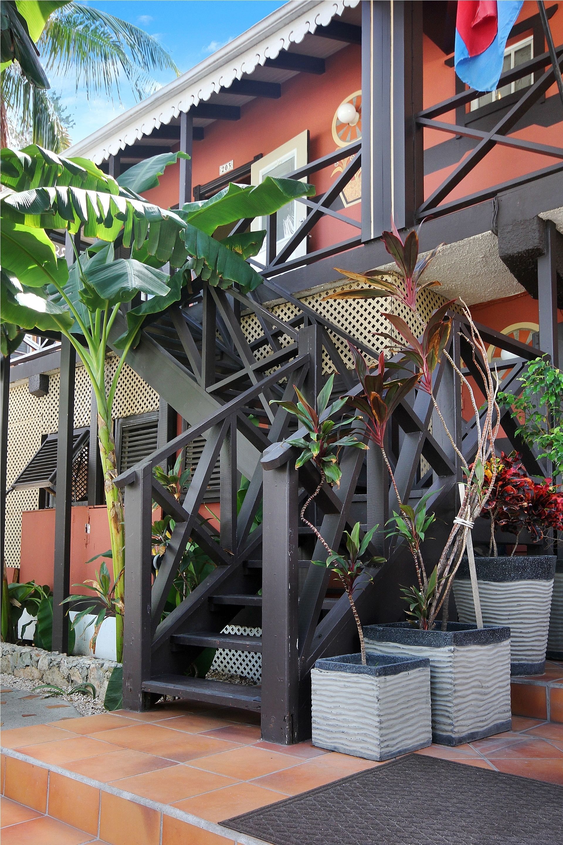 A building with a staircase, potted plants, and a tiled entrance area.