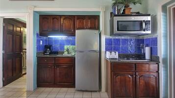 Una cocina con armarios de madera, un refrigerador de acero inoxidable, un microondas y un lavamanos.