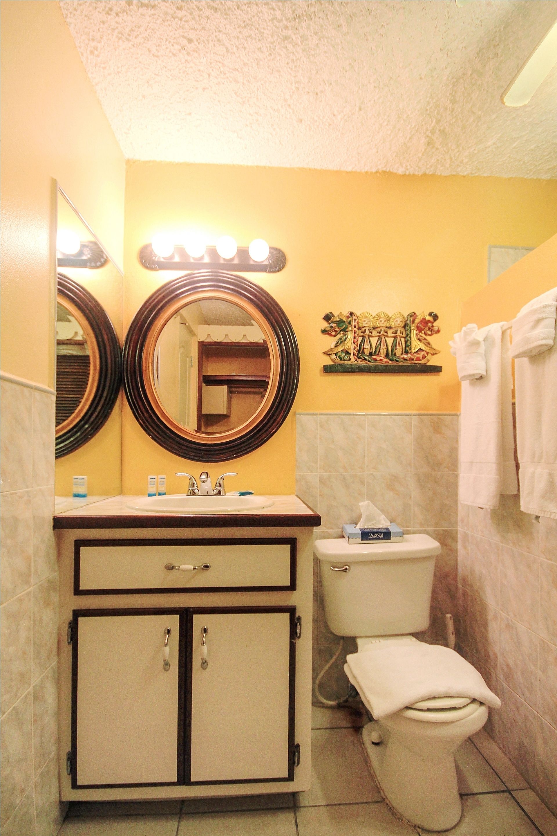 A bathroom with two mirrors, a sink, a toilet, and a towel rack.