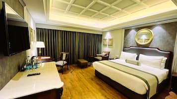 A hotel room with a large bed, a desk, a chair, a TV, and a mirror.