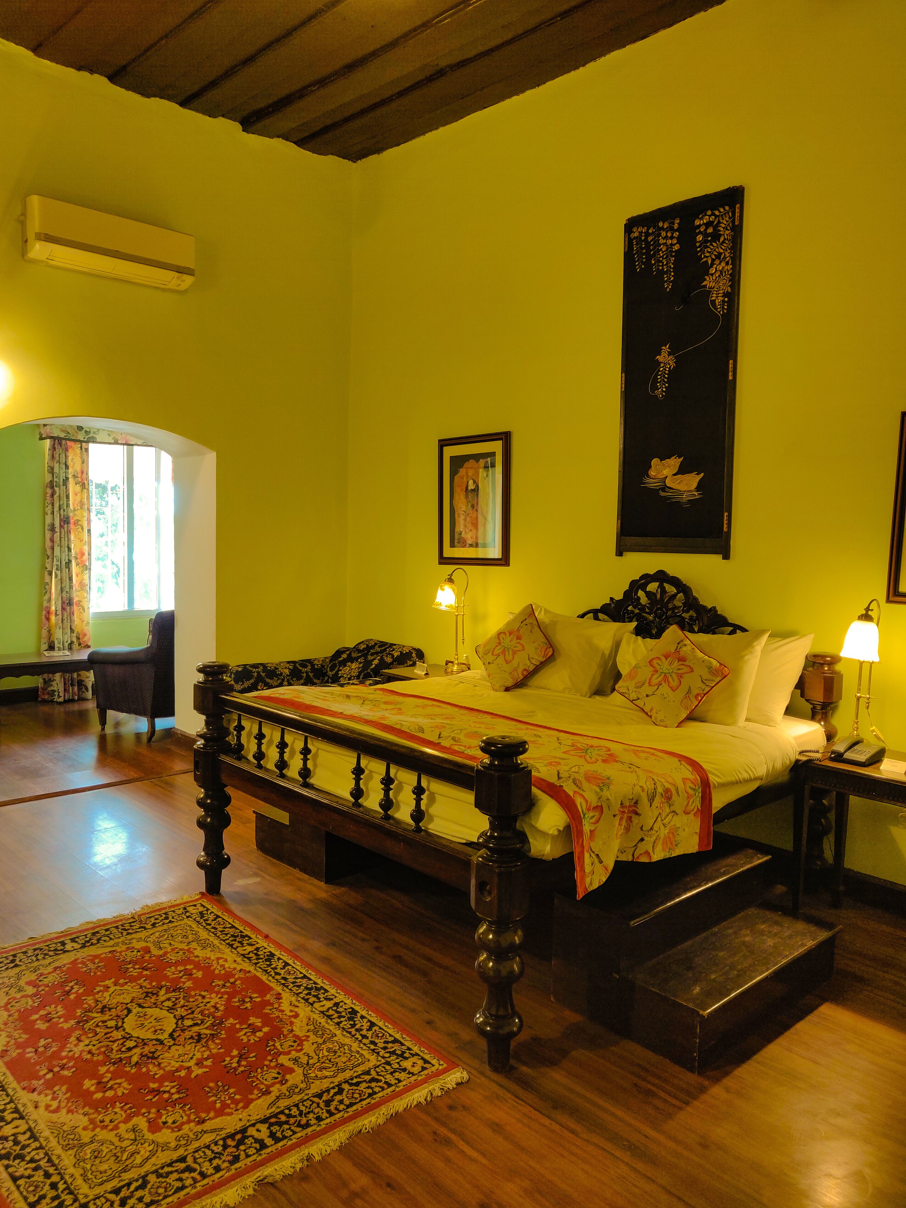 Una habitación con cama, silla, lámpara y alfombra.