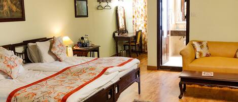 A bedroom with a wooden bed, a wooden desk, a mirror, a yellow sofa, and a patterned rug.