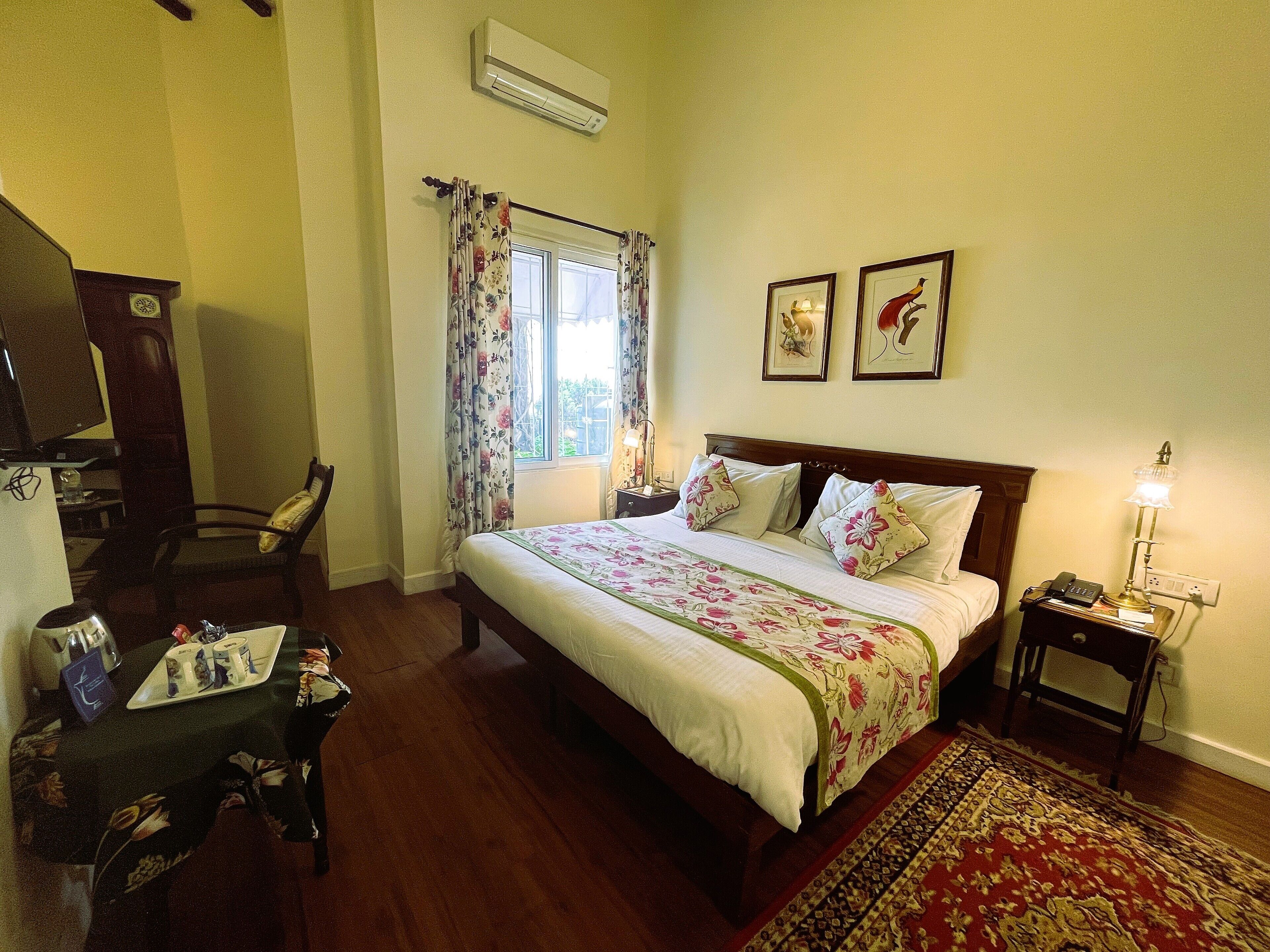 A neatly arranged bedroom with a bed, a desk, a chair, and a nightstand with a lamp.