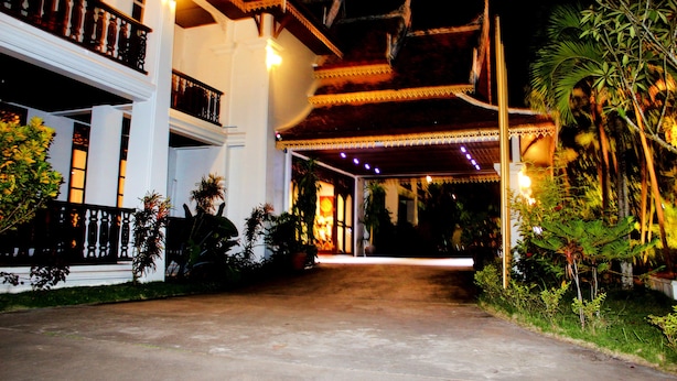 A traditional building with a covered entrance, white walls, and a balcony with ornate railings.