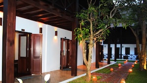 A covered outdoor area with a brick pathway, wooden pillars, and a tree.