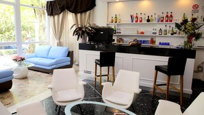 Un hall d’hôtel moderne doté d’un bar, de différents espaces pour s’asseoir et d’une grande fenêtre offrant une vue sur l’extérieur.