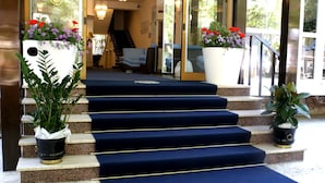 L’entrée d’un hôtel, avec un escalier recouvert d’une moquette bleue menant à l’accueil.