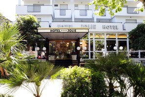 A hotel entrance with a covered porch, potted plants, and a white facade. - New Hotel Jolie (Rimini)