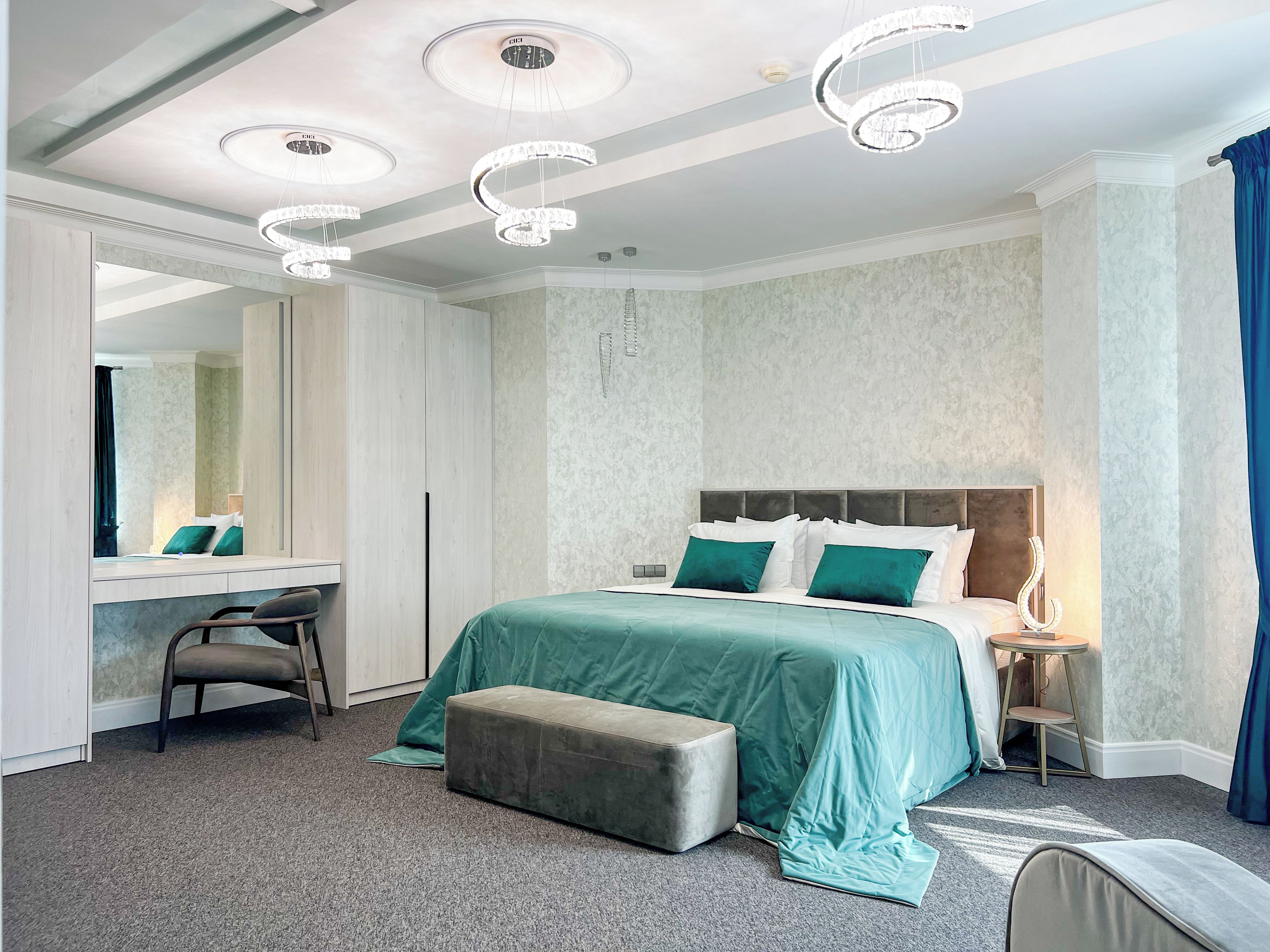A hotel room with a large bed, a desk, a chair, and a mirror.