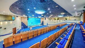 A conference room with a stage, blue carpet, and rows of chairs. - Hotel Victoria Minsk (Minsk)