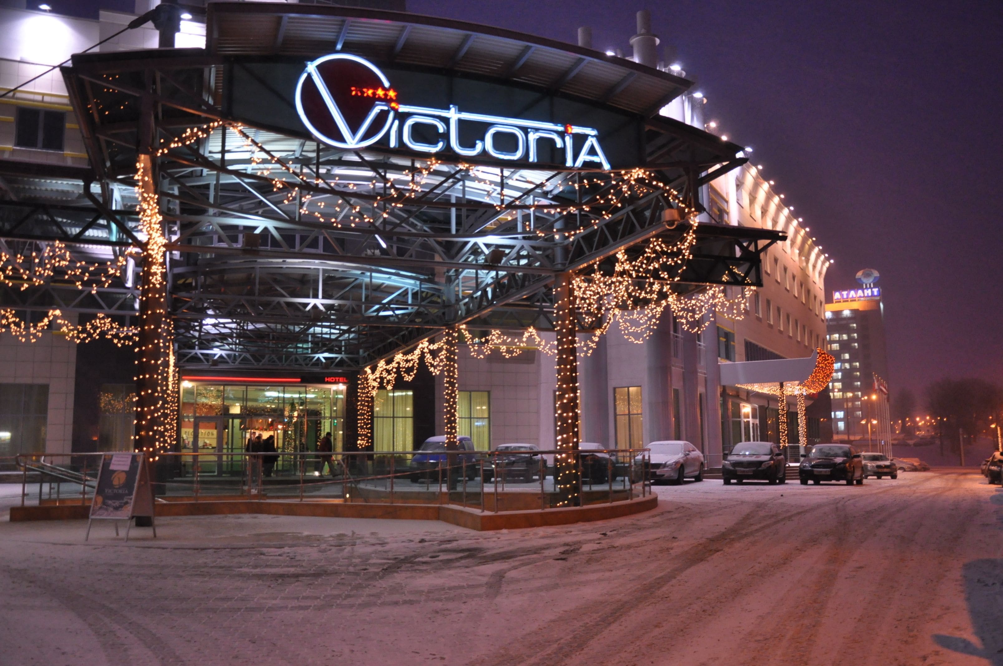A hotel entrance with a covered area, illuminated signage, and a parking lot.