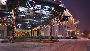 A hotel entrance with a covered area, illuminated signage, and a parking lot.